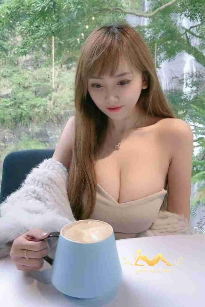 Attractive Asian woman with coffee, wearing off-shoulder top and shawl.