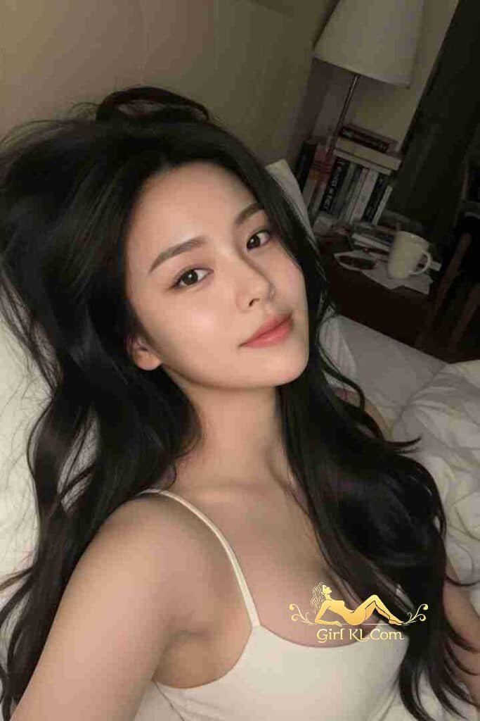 Elegant Asian woman with long dark hair in a white top. Soft lighting, serene expression.