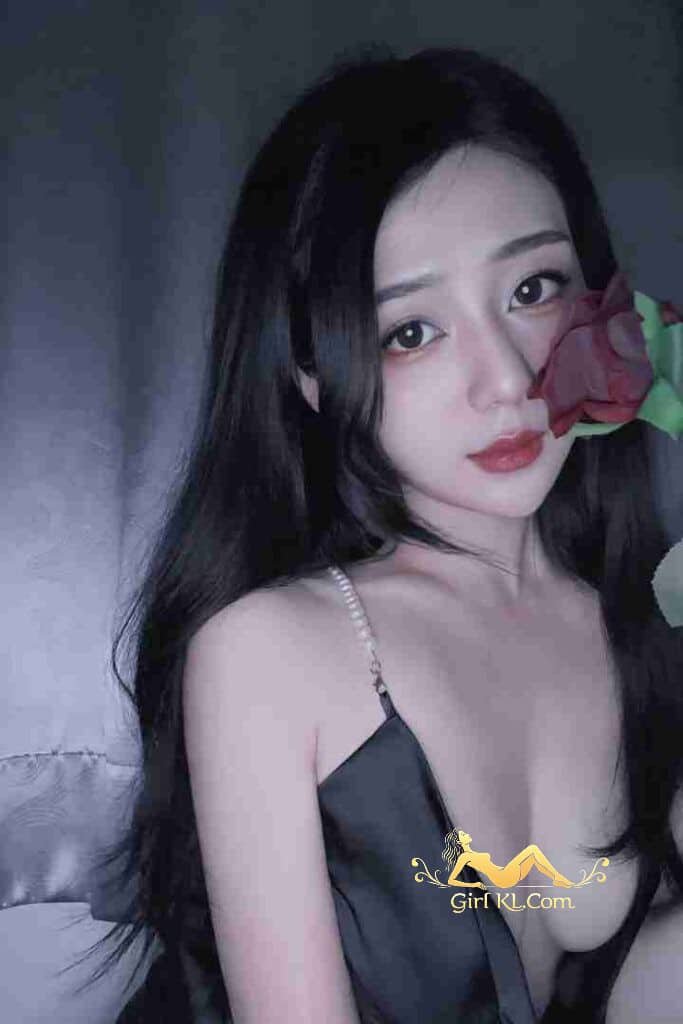 Beautiful Asian woman with rose, wearing black dress, dark hair, soft lighting.