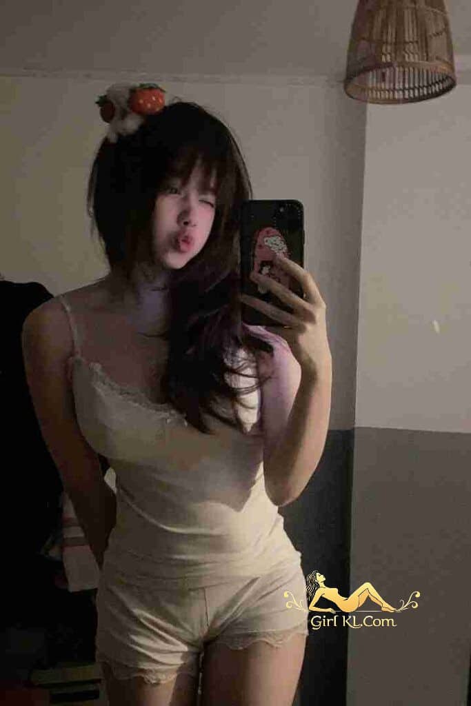 Cute Asian woman in tank top and shorts taking selfie.