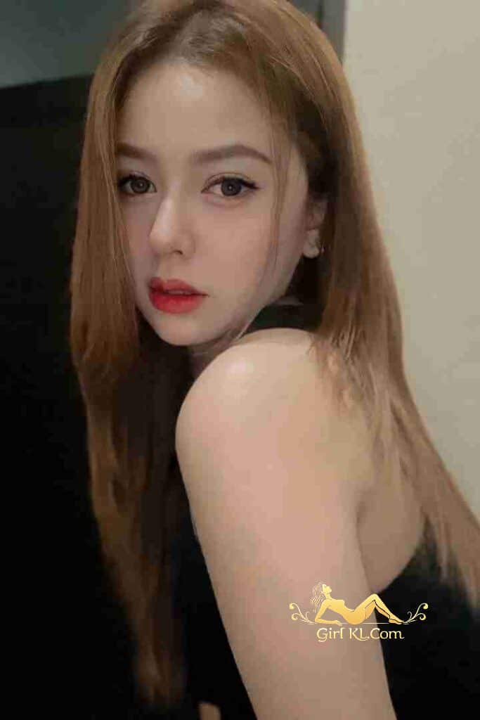 Attractive Malay girl looking over shoulder with red lipstick and long brown hair.