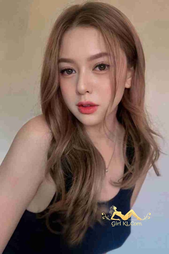 Attractive woman with light brown hair and coral lipstick against a neutral background.