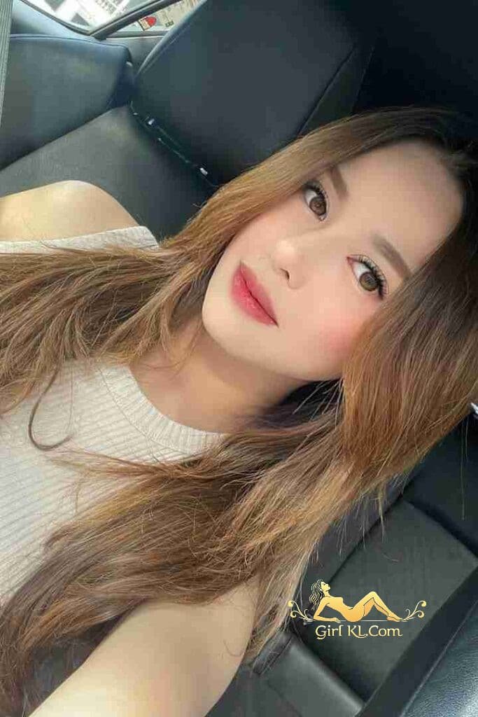 Portrait of a beautiful woman with long brown hair and light makeup, sitting in a car.