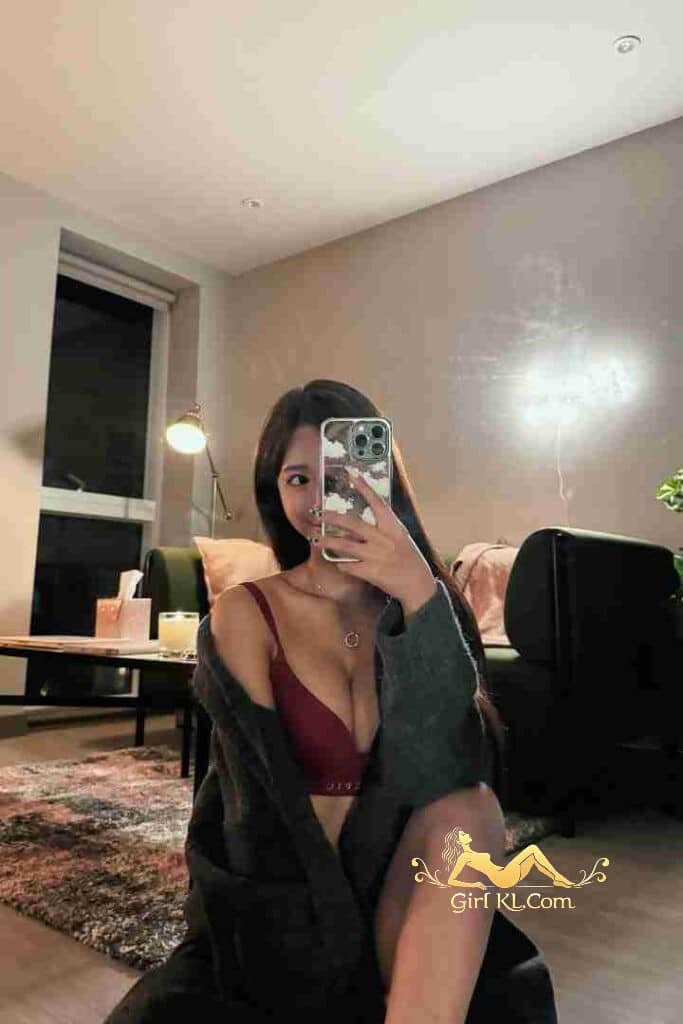 Jia Ying, Kuala Lumpur escort, in red bra and grey robe taking selfie.