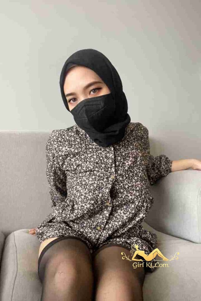 Malay woman in hijab and mask on sofa