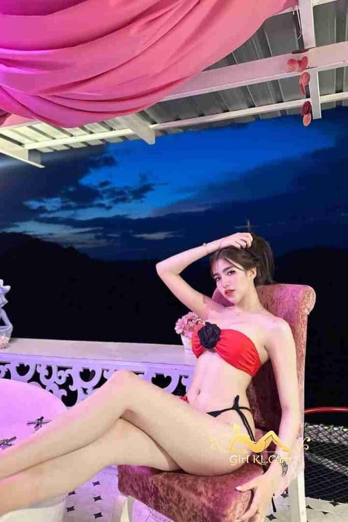 Thai call girl Arisa, in red bikini, posing outdoors. KL escort services.