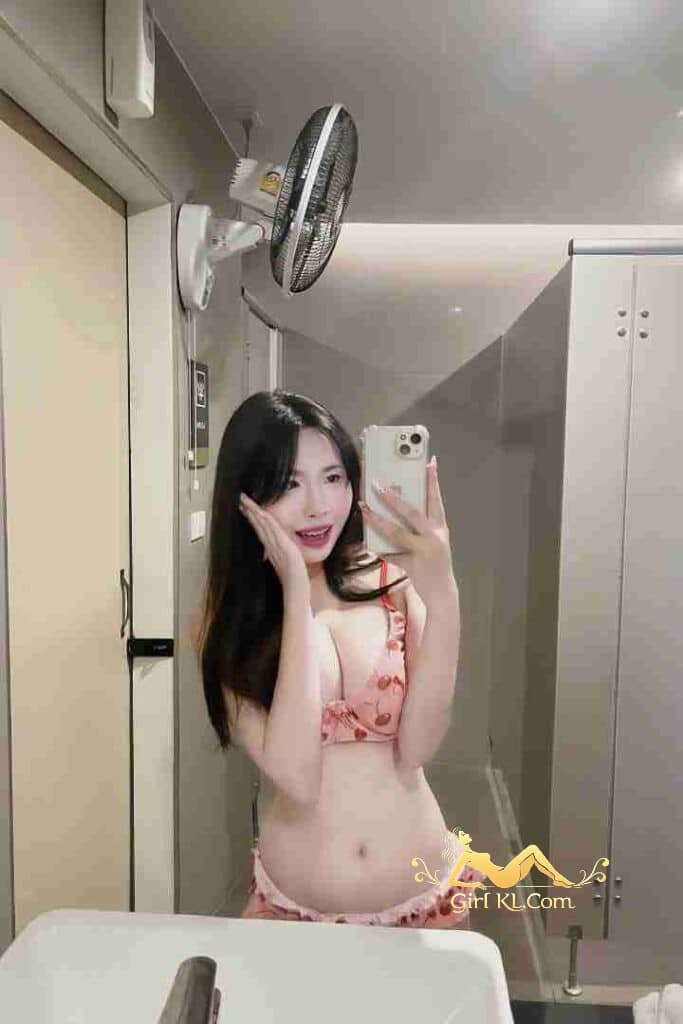 Stunning Thai escort Lena in pink lingerie taking a selfie in a bathroom.
