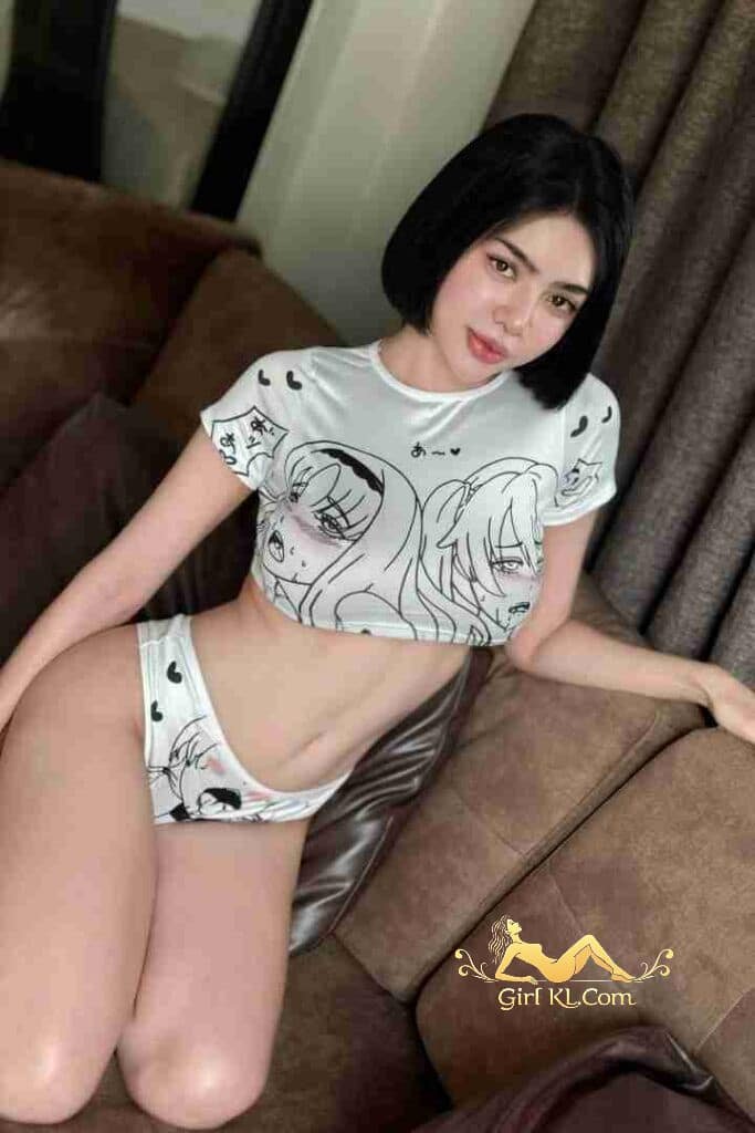 Thai woman in anime-print lingerie set on couch. KL Escort.