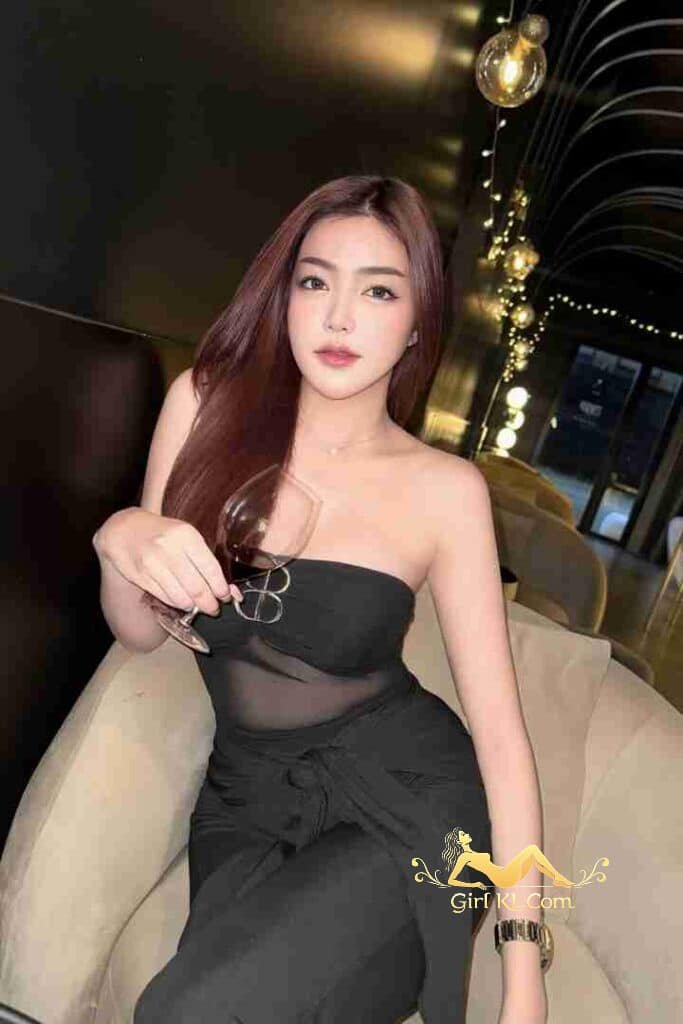 Elegant Thai woman in black dress holding wine glass, Kuala Lumpur call girl.