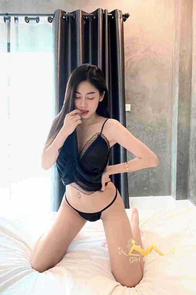 Sexy Thai woman in lingerie kneeling on bed. KL Escort Nori. C cup curves.