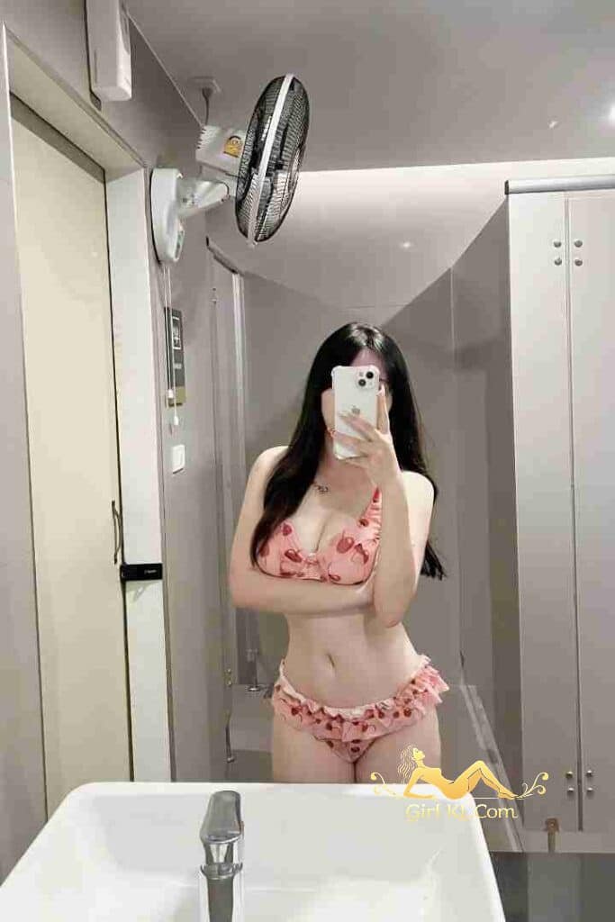 Thai woman in pink bikini taking mirror selfie in bathroom. KL escort beauty.