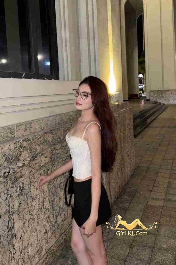 Vietnamese woman in white corset top and black skirt posing outdoors at night.
