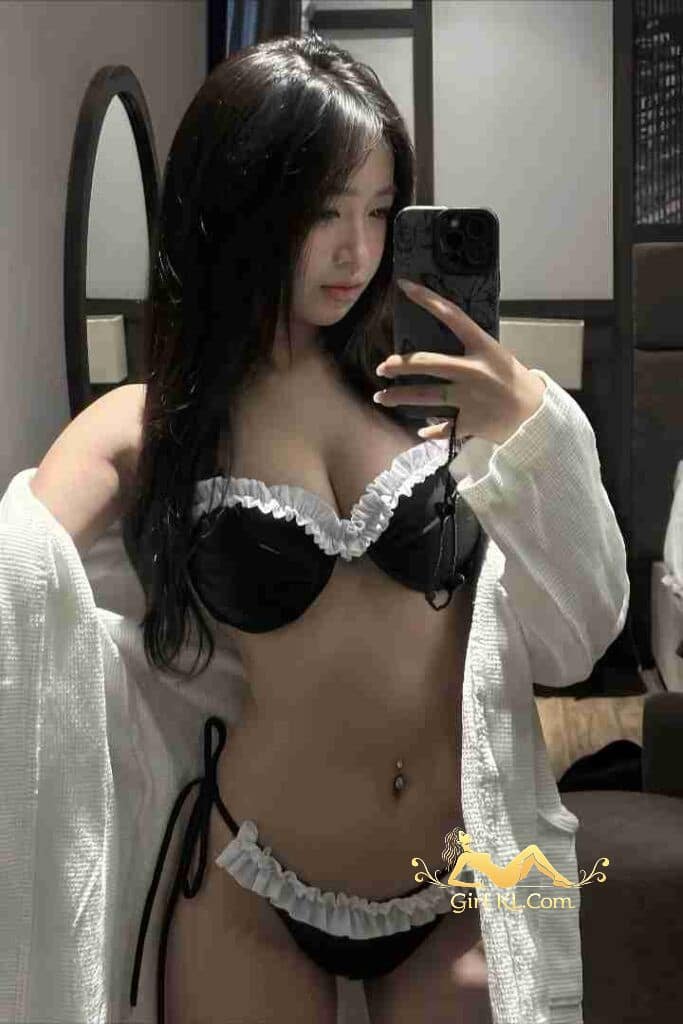 Sexy Vietnamese woman in lingerie taking selfie with phone.