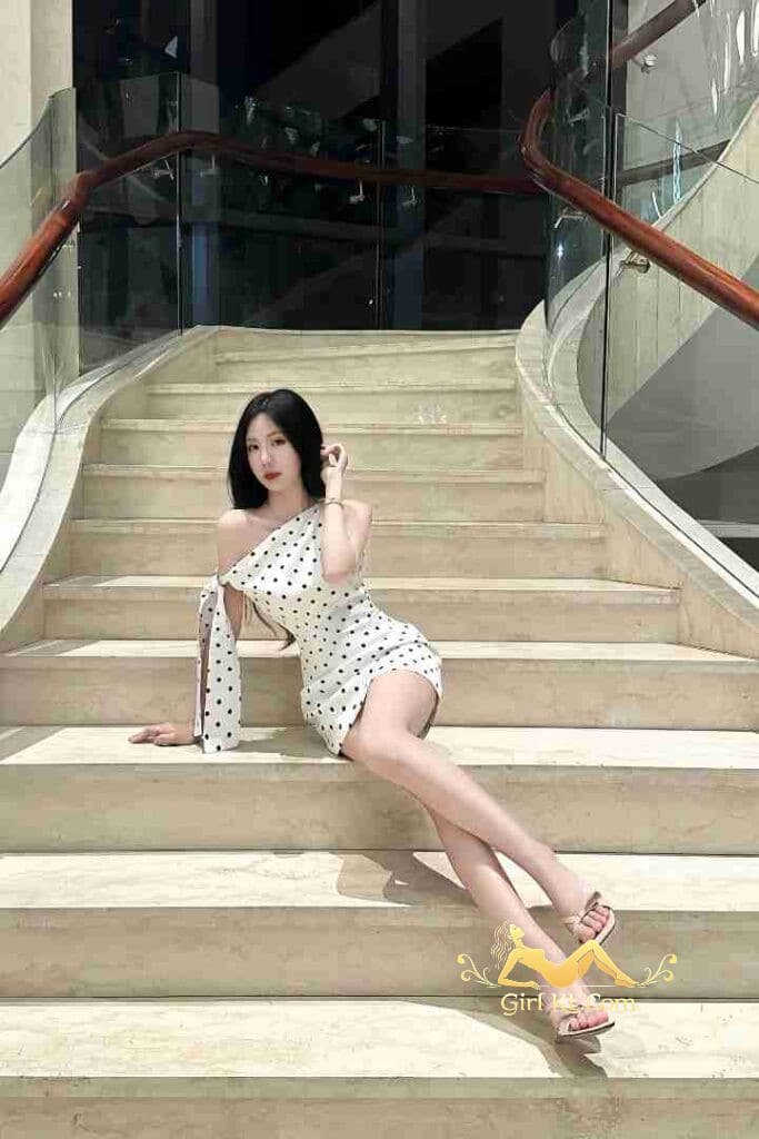 Vietnamese woman in polka dot dress on stairs, Kuala Lumpur escort.
