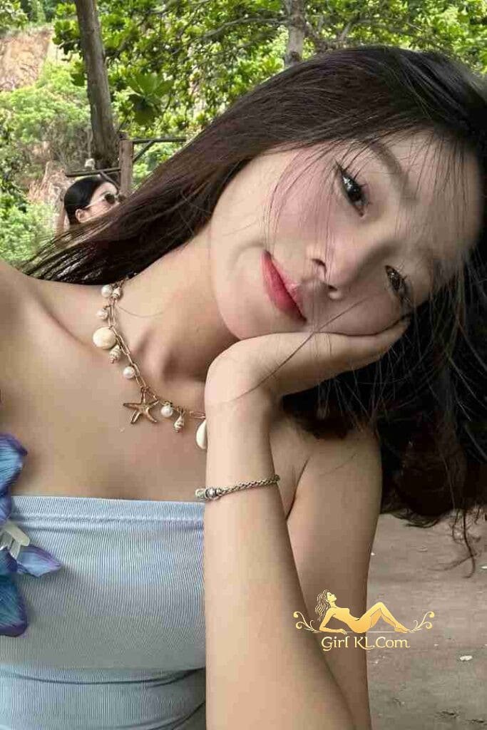 Beautiful Vietnamese woman with seashell necklace smiling at the beach.