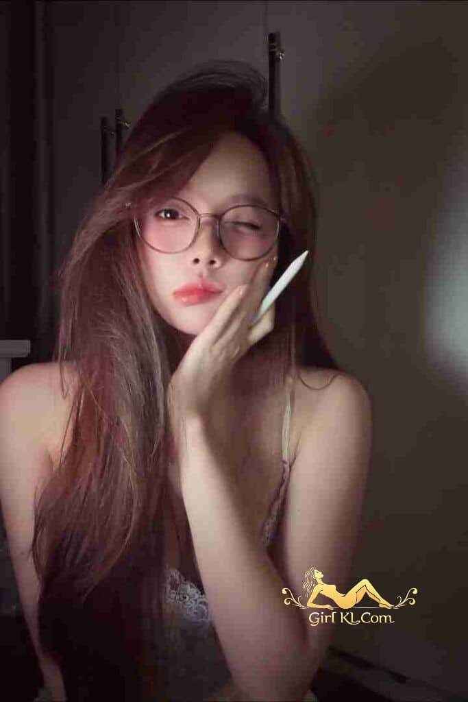 Attractive woman with glasses holding stylus, winking. Possibly Vietnamese escort, based on page title.