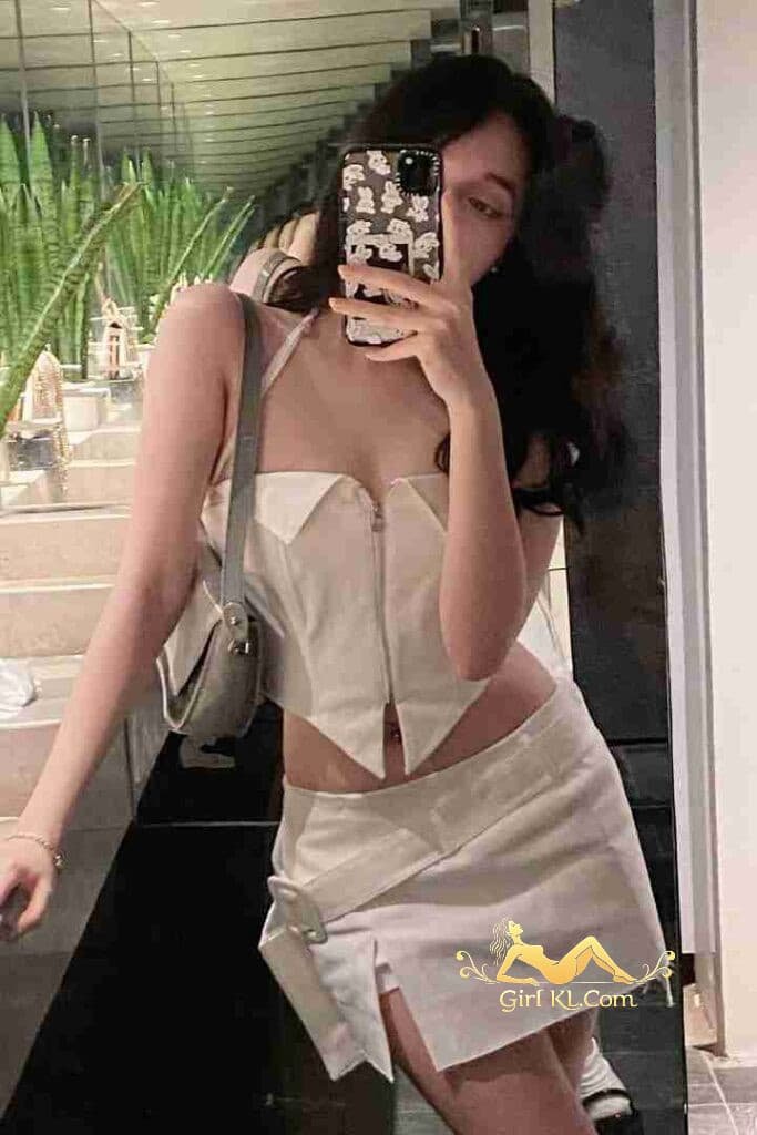 Woman in white outfit takes mirror selfie. Gray purse, C cup.