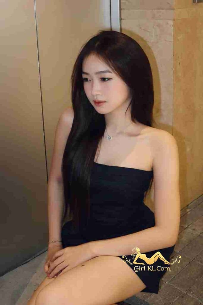 Attractive young Asian woman in black strapless dress, long dark hair, looking away.