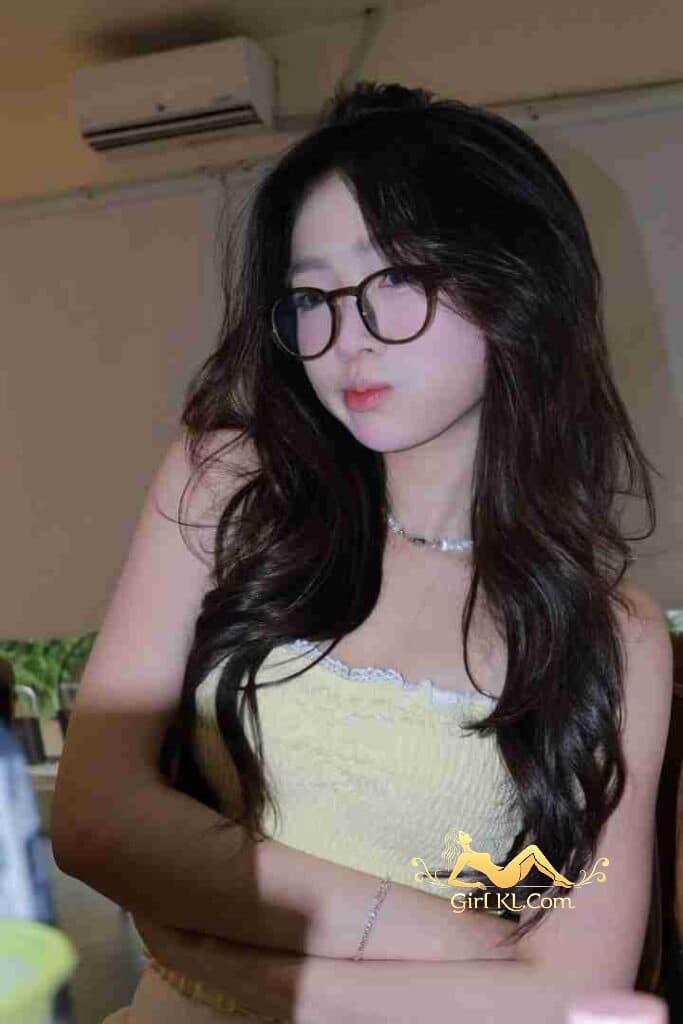 Young woman with glasses and wavy hair in yellow top. Pretty Asian woman portrait.