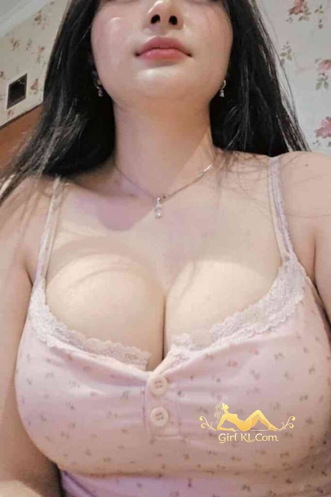 Busty Asian woman in pink top with lace, silver necklace.